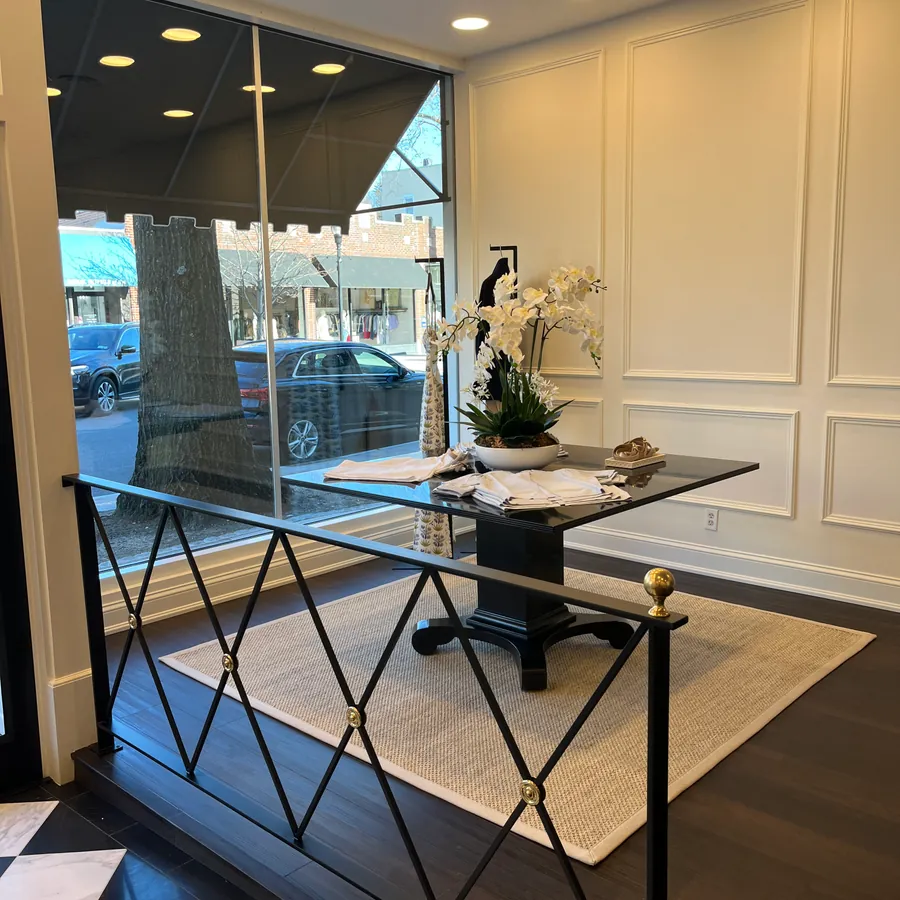 A black table with white orchids in the front window, behind a black and brass railing