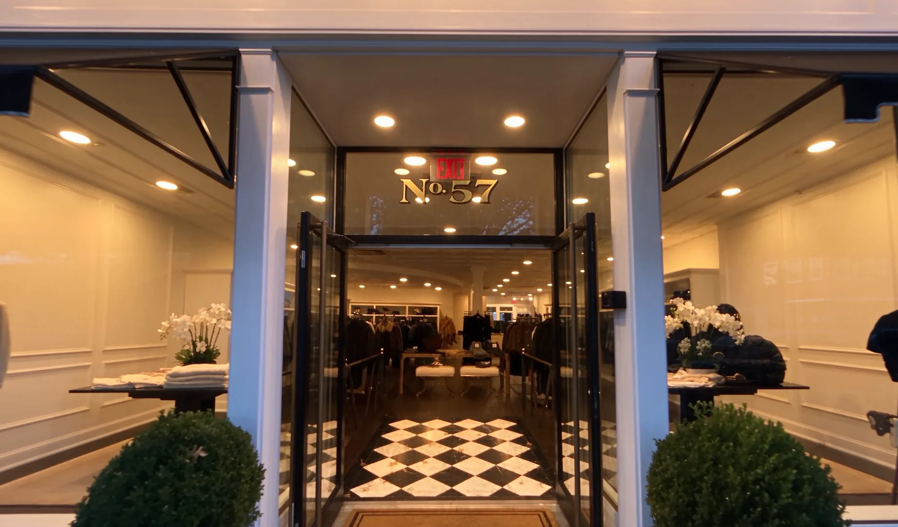 Looking through the open front doors of Baxter in Rye, under the gold No. 57 transom, into the lit store